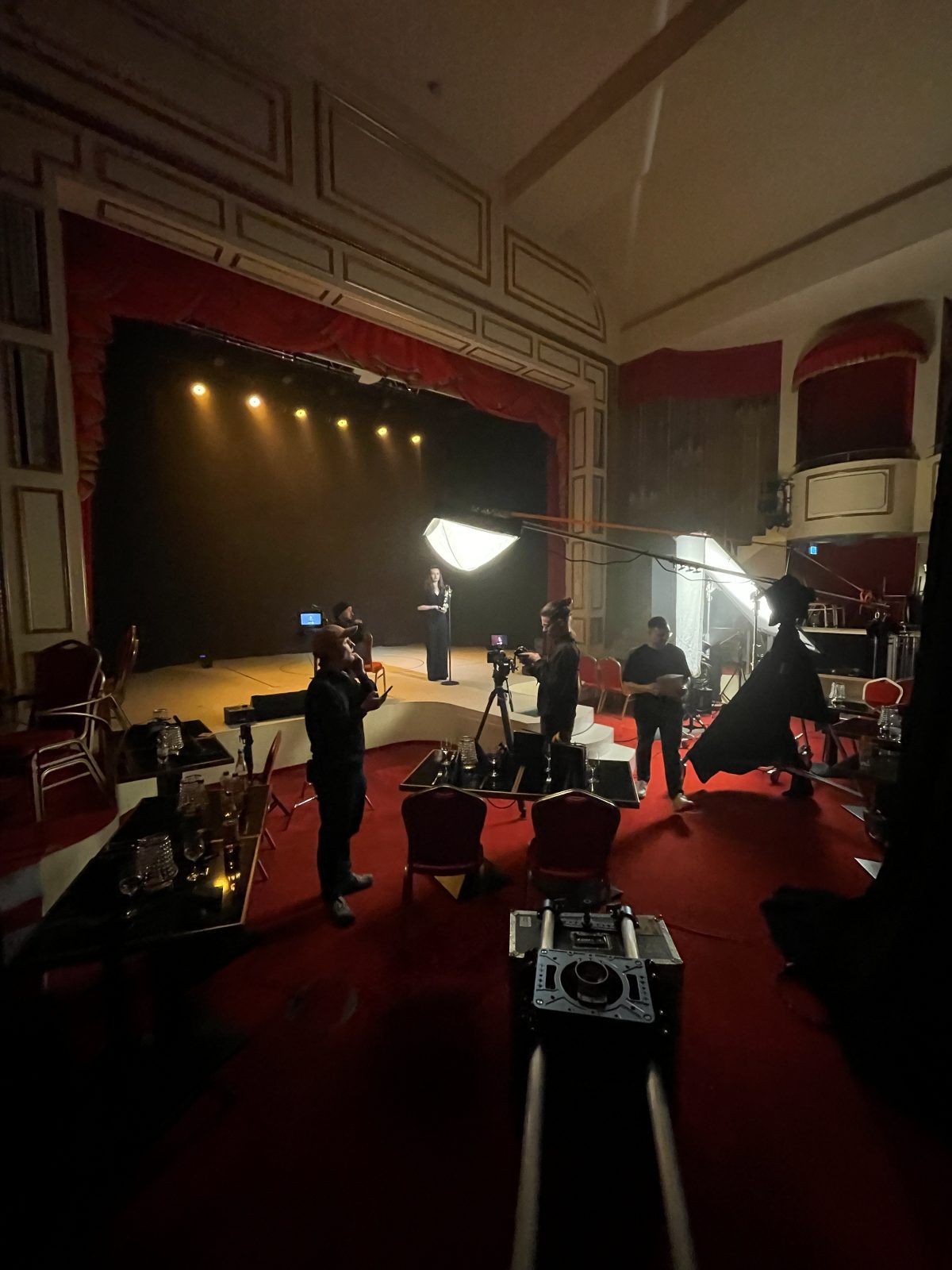 Dreh in einem alten Theatersaal mit roten Rängen: Team und Softbox auf der Bühne