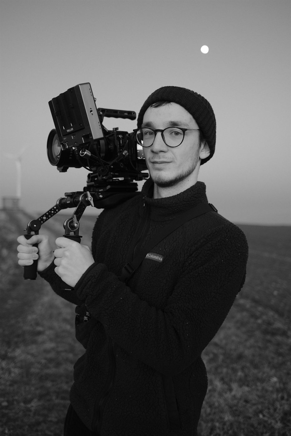 Niklas Reimann mit Schulterrig und Kamera auf einem Feld in der Dämmerung