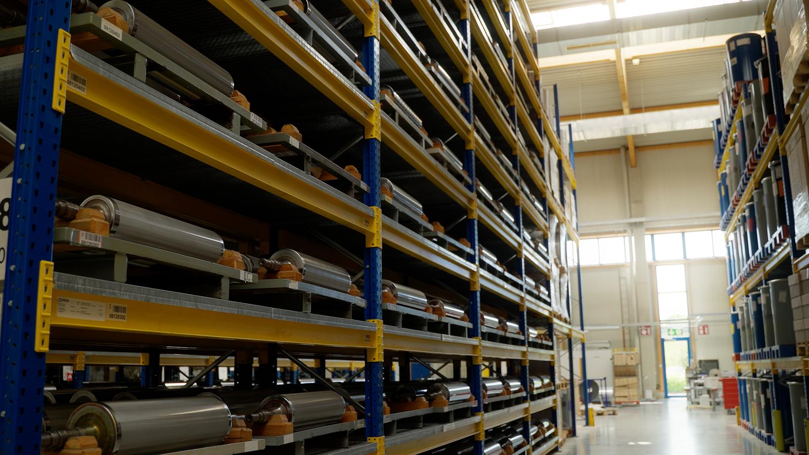 Hochregallager mit Materialrollen auf Paletten, Blick in die Halle