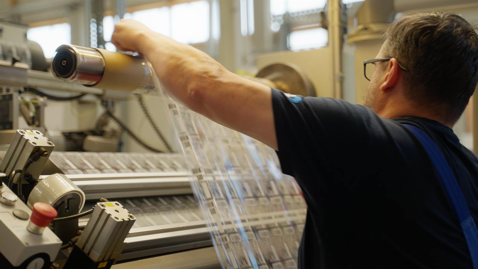 Mitarbeiter richtet eine Materialrolle an der Druckmaschine ein