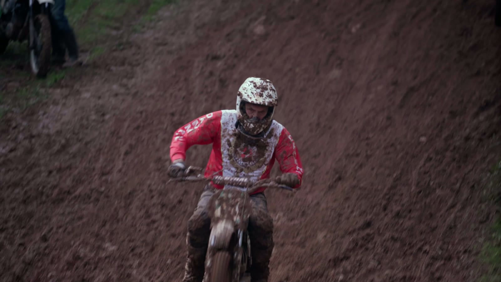 Motocross-Fahrer frontal im Schlamm, Blick in die Kamera