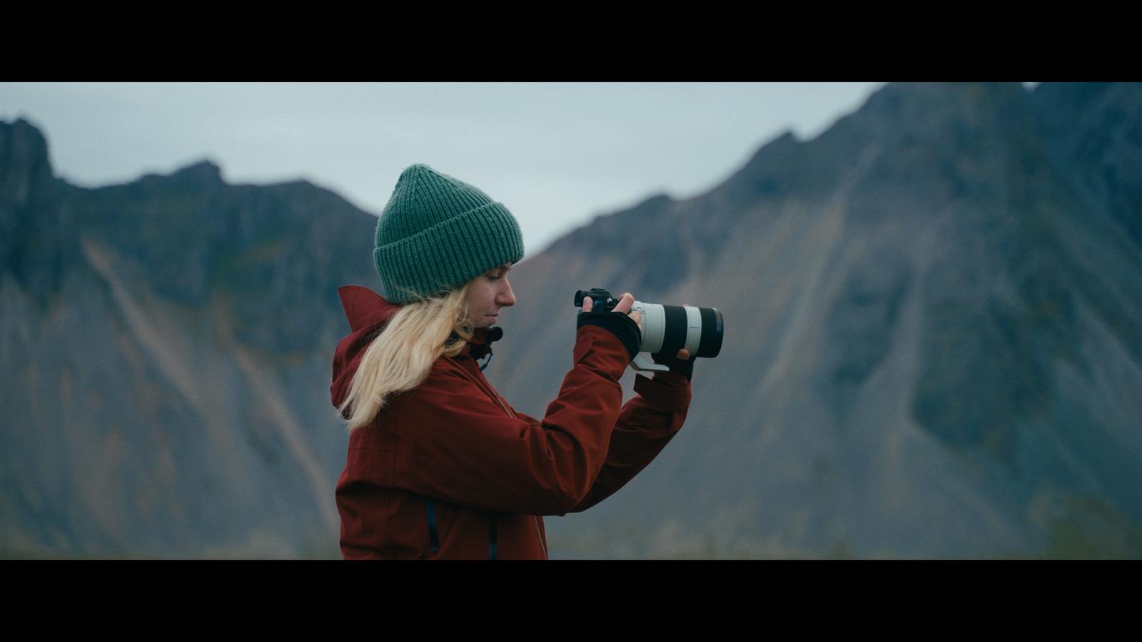 Frau mit Kamera fotografiert vor einer Bergkulisse