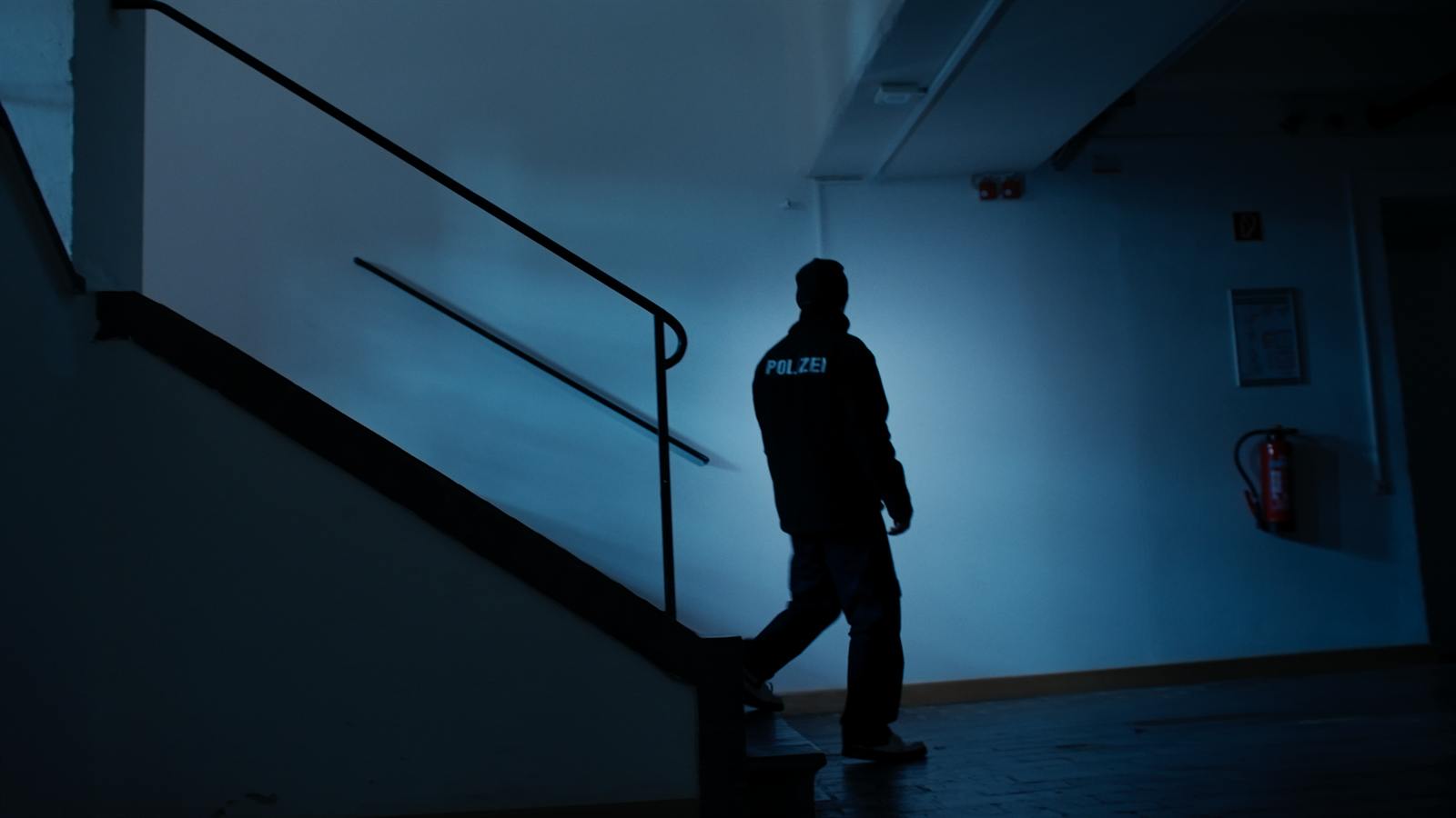 Silhouette eines Polizisten in einem dunklen Treppenhaus