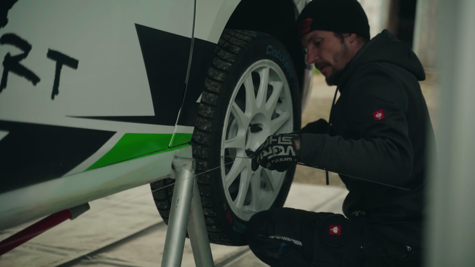 Mechaniker montiert ein Rad am aufgebockten Rallyewagen